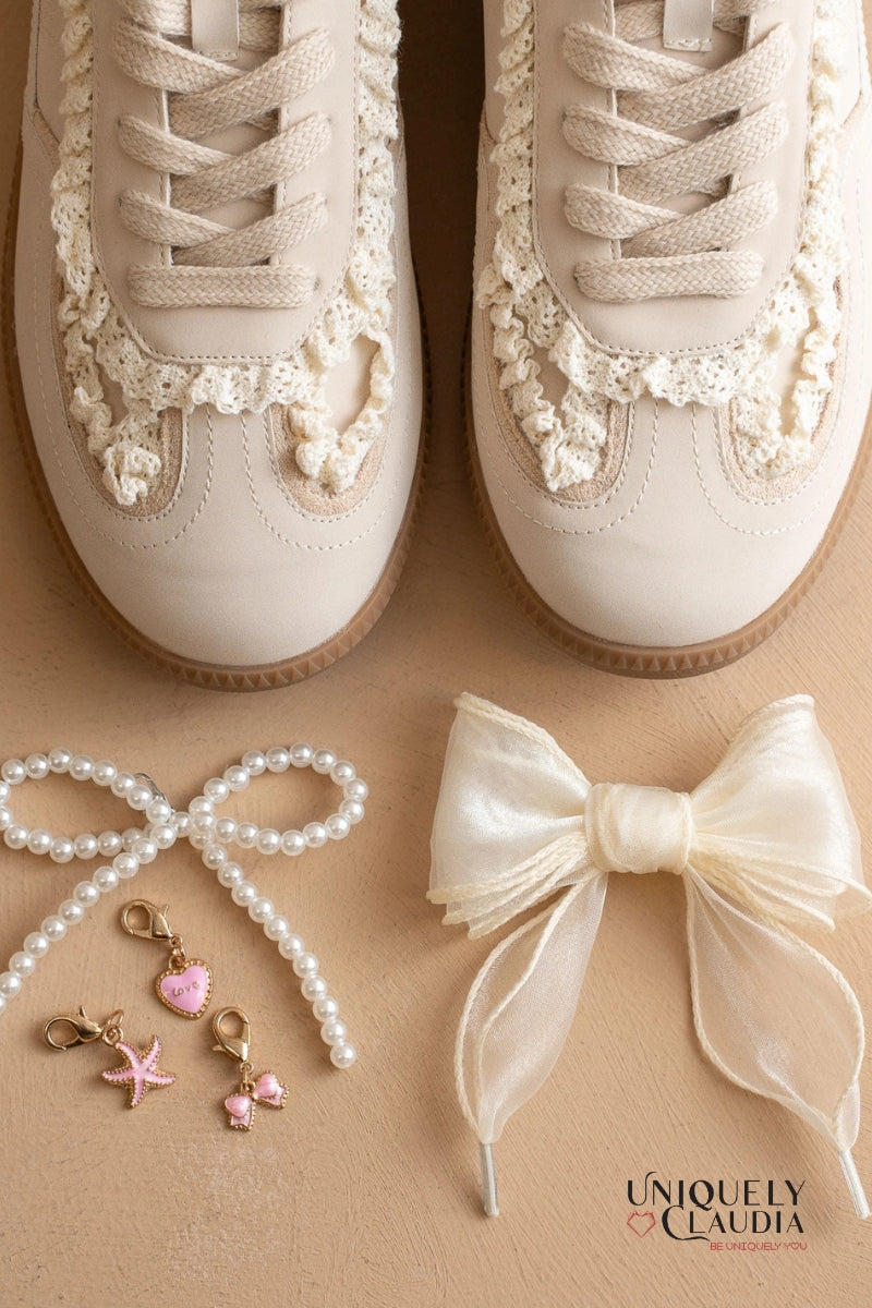 Beige sneakers with lace details, pearl accessories, and a bow on a beige background.