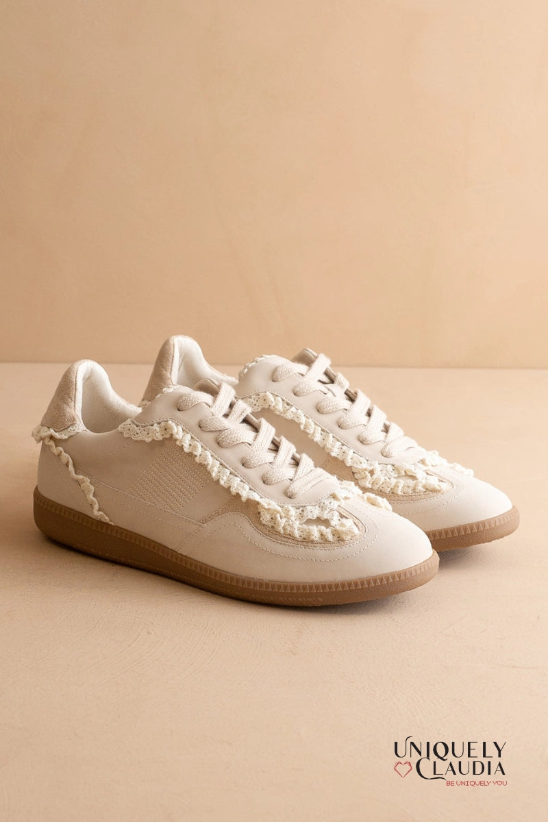 White sneakers with lace details on a beige background