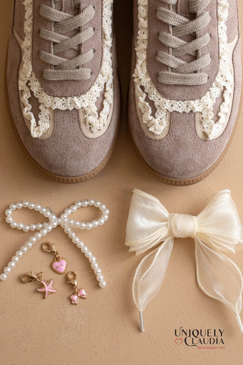 Pair of lace-up shoes with decorative elements on a beige background, featuring the brand 'Uniquely Claudia'.