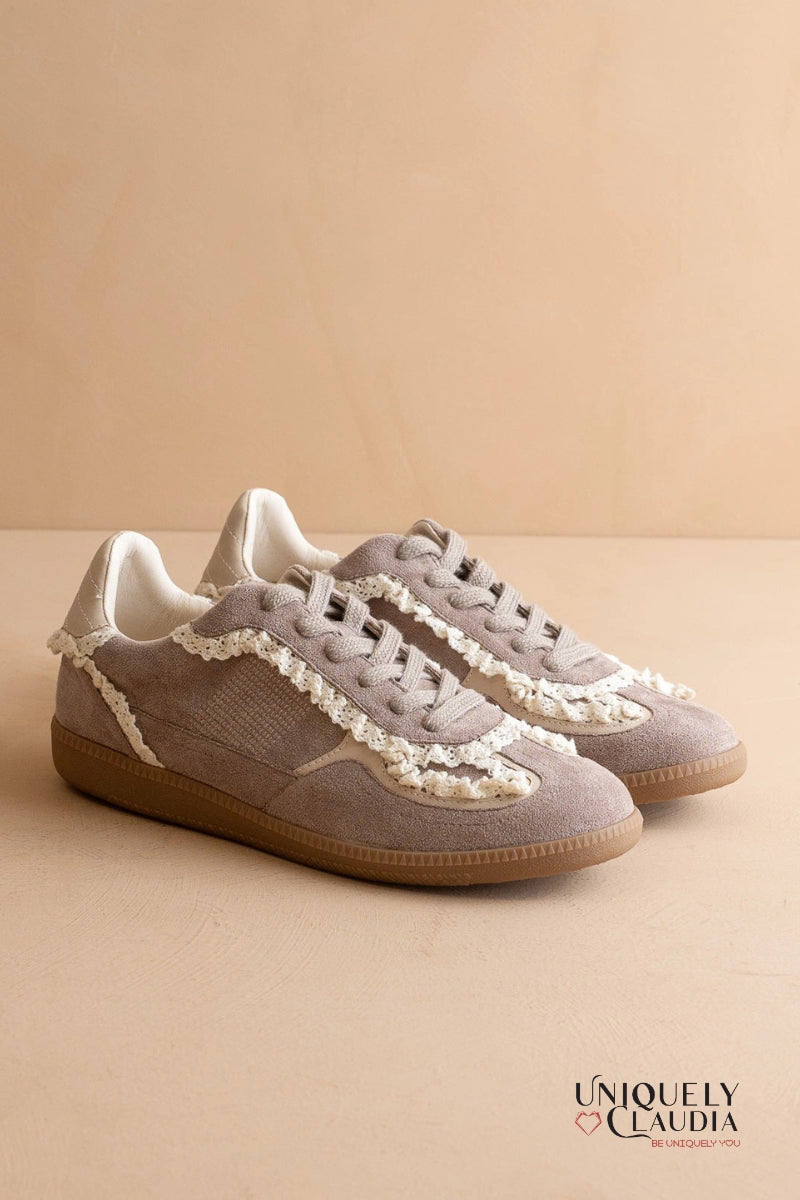 Pair of gray sneakers with white lace details on a beige background, featuring the brand 'UNiquely Claudia'.