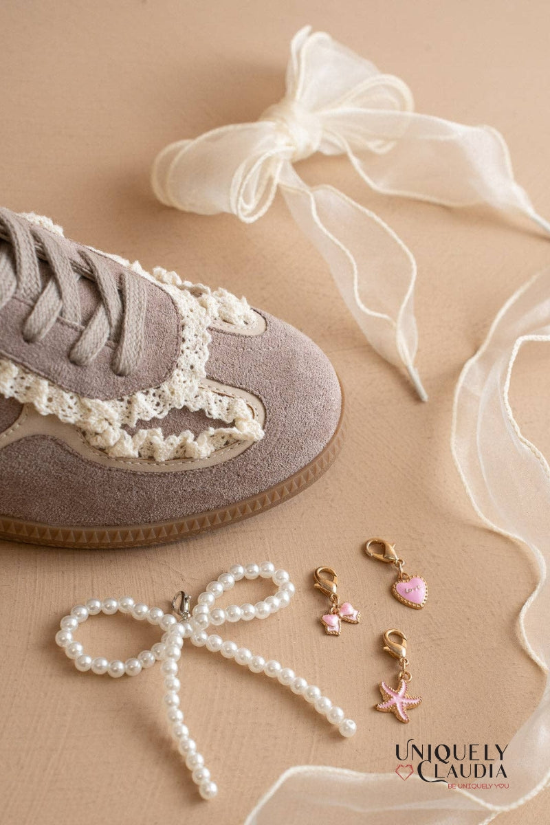 Sneaker with lace details, pearl accessories, and decorative ribbons on a beige background.