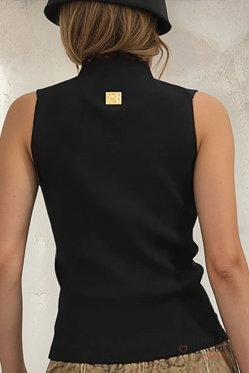 Person wearing a black sleeveless top with a visible brand logo on a neutral background