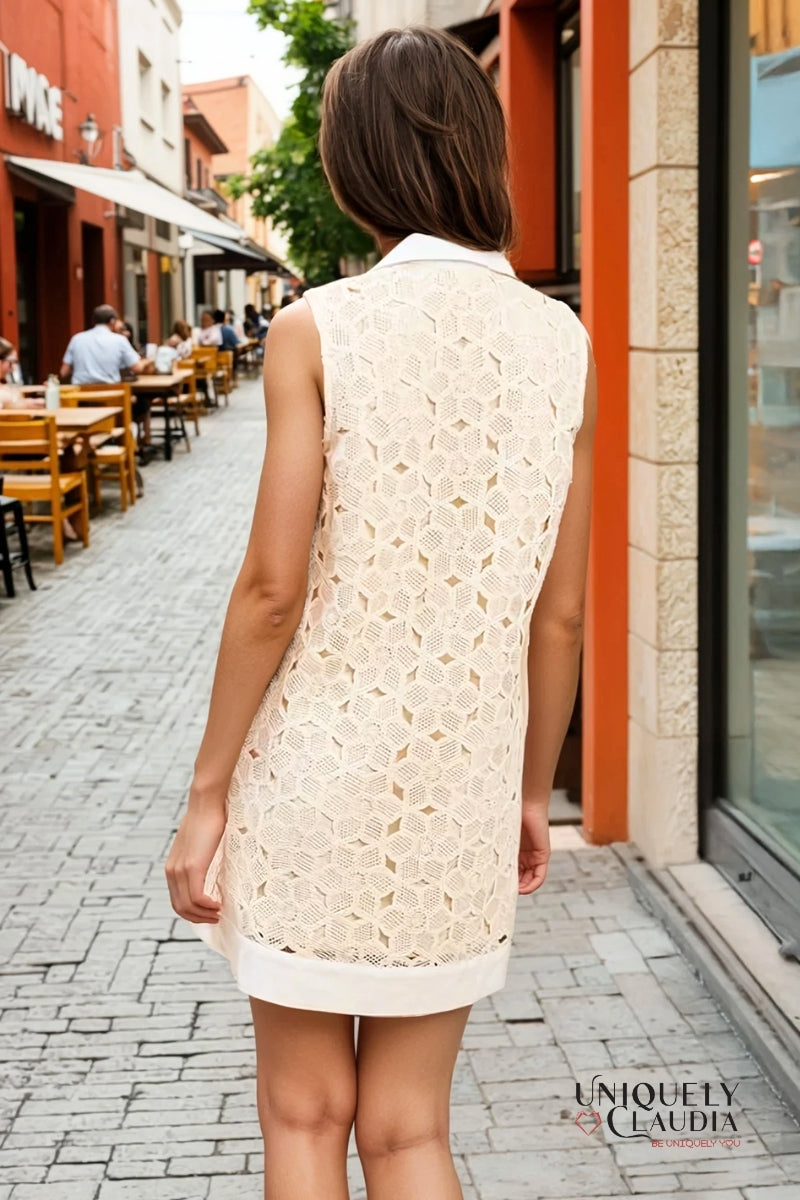 Woman wearing a white lace dress walking on a street with shops and tables.