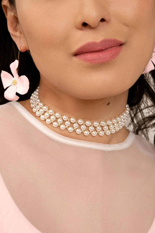 Close-up of a person wearing a pearl necklace with a blurred background