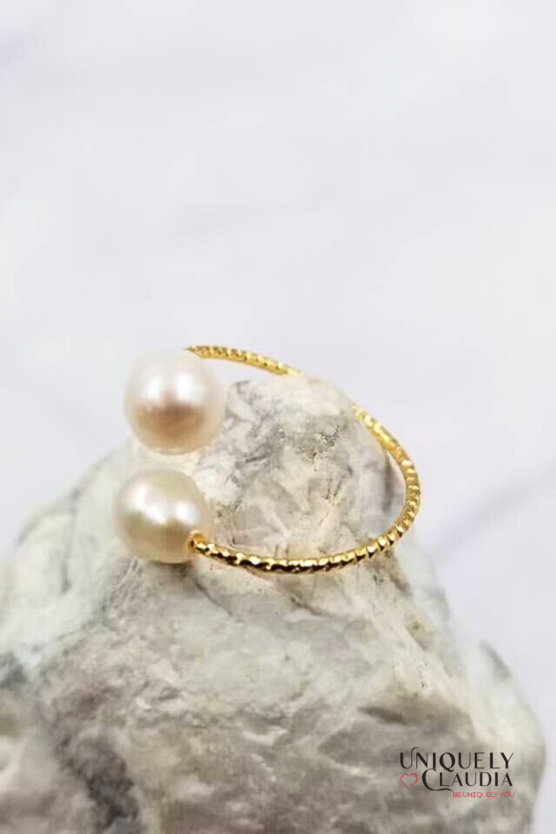 Gold bracelet with pearls on a marble surface, brand 'Uniquely Claudia' visible