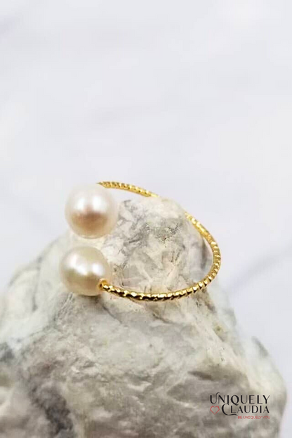 Gold bracelet with pearls on a marble surface, brand 'Uniquely Claudia' visible