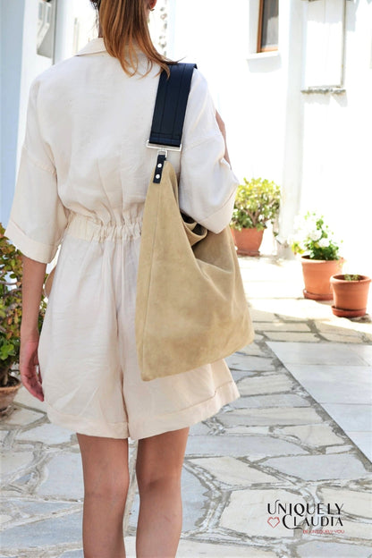 Person wearing a beige tote bag outdoors on a stone path with plants.