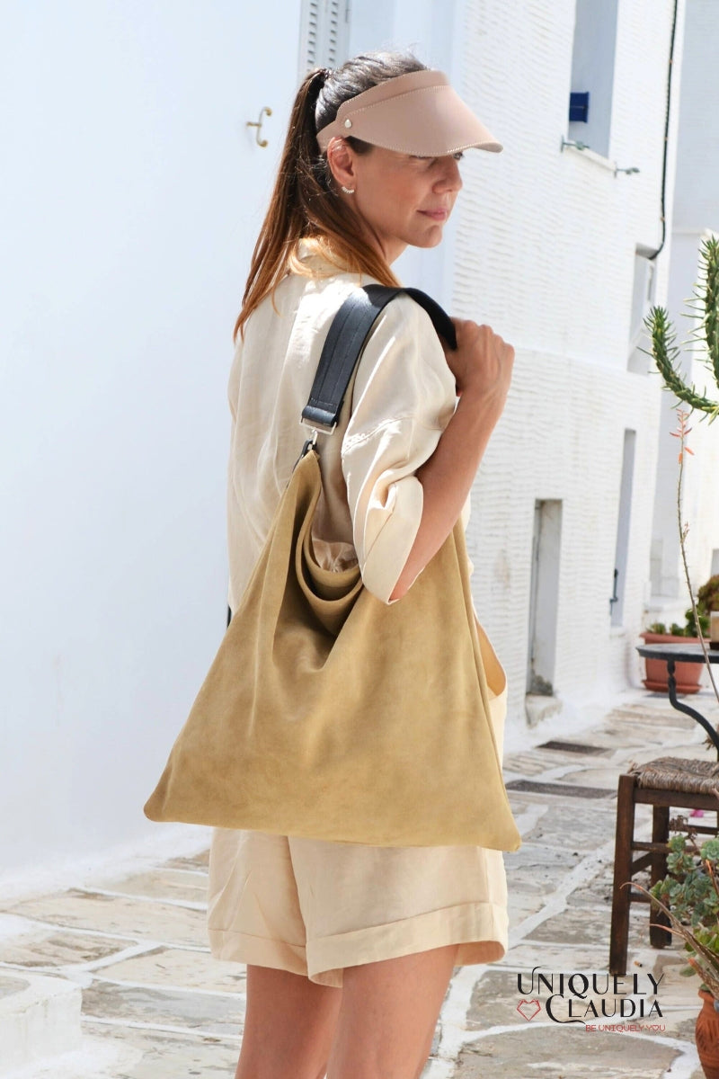 Woman carrying a beige tote bag in an outdoor setting with white walls and wooden floors.