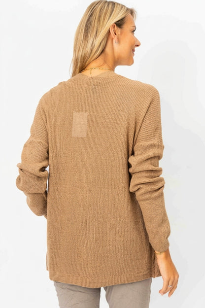 A woman shown from the back wearing a tan ribbed knit long-sleeve sweater and light gray pants against a plain white background.
