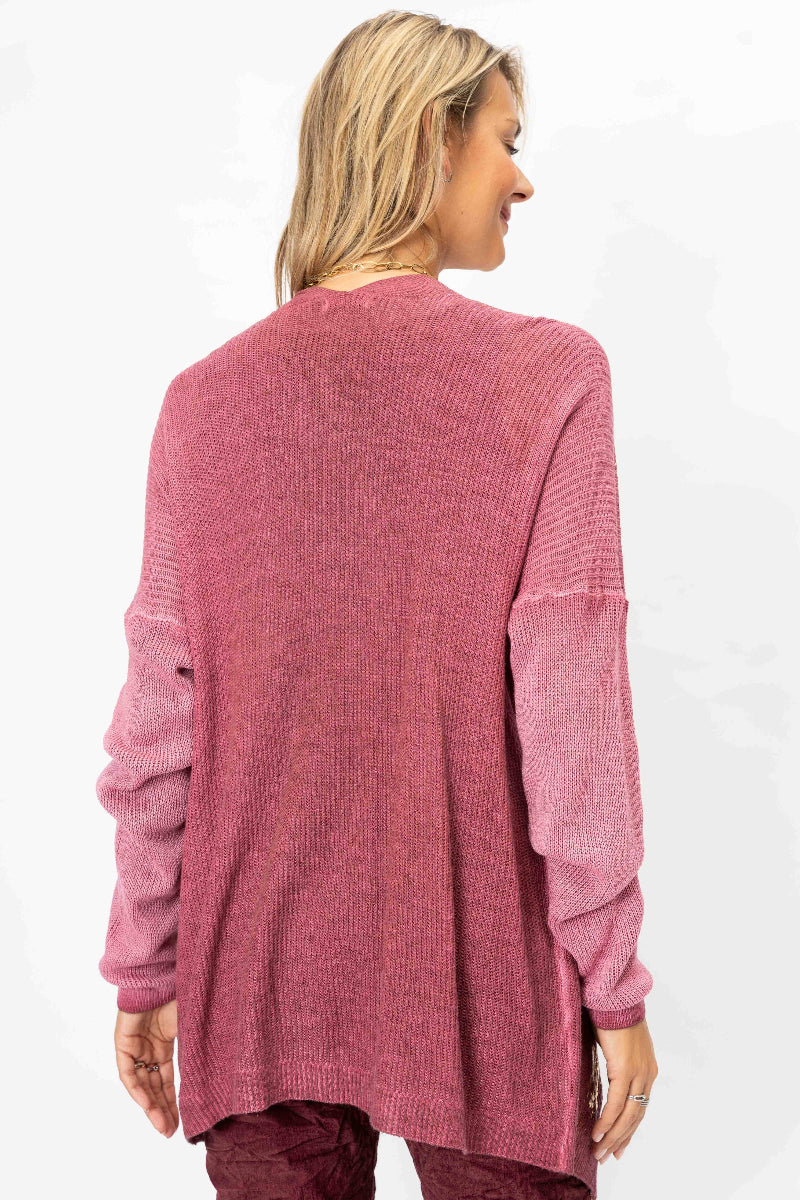A woman shown from the back wearing a dusty rose ribbed knit cardigan sweater with textured sleeves, set against a plain white background.