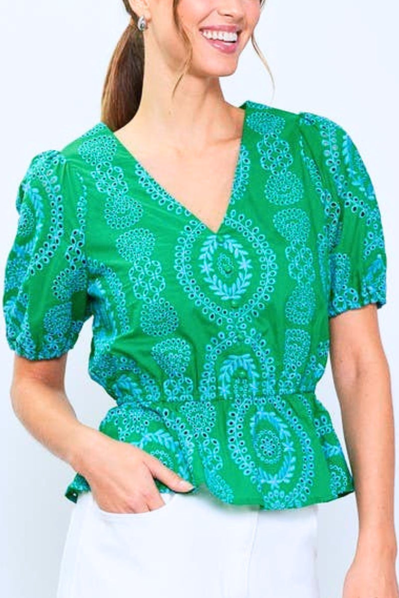 Woman wearing a green patterned blouse against a white background