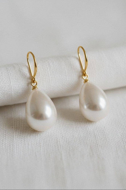 Pearl earrings with gold hooks on a white fabric background