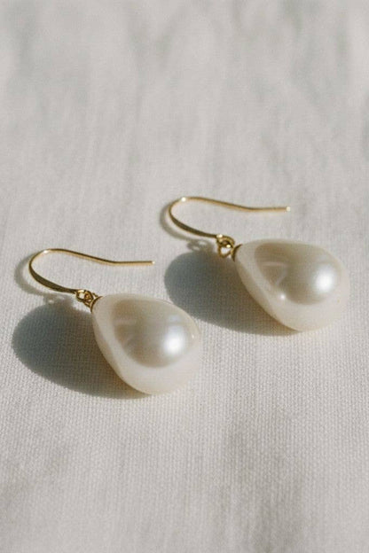 Pearl earrings with gold hooks on a light fabric background