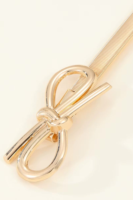 Gold bow-shaped hair clip on a light beige background