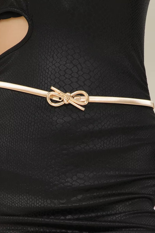Black textured dress with a gold bow belt on a neutral background