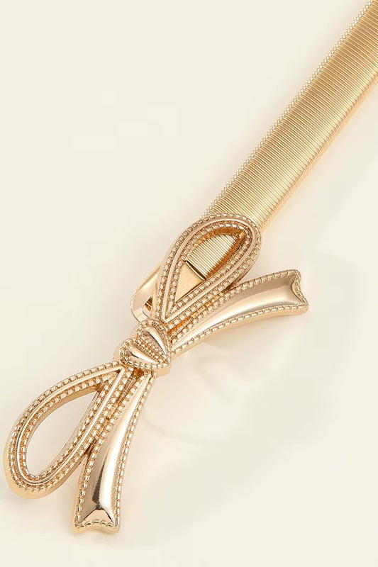 Gold hair comb with decorative bow on a beige background
