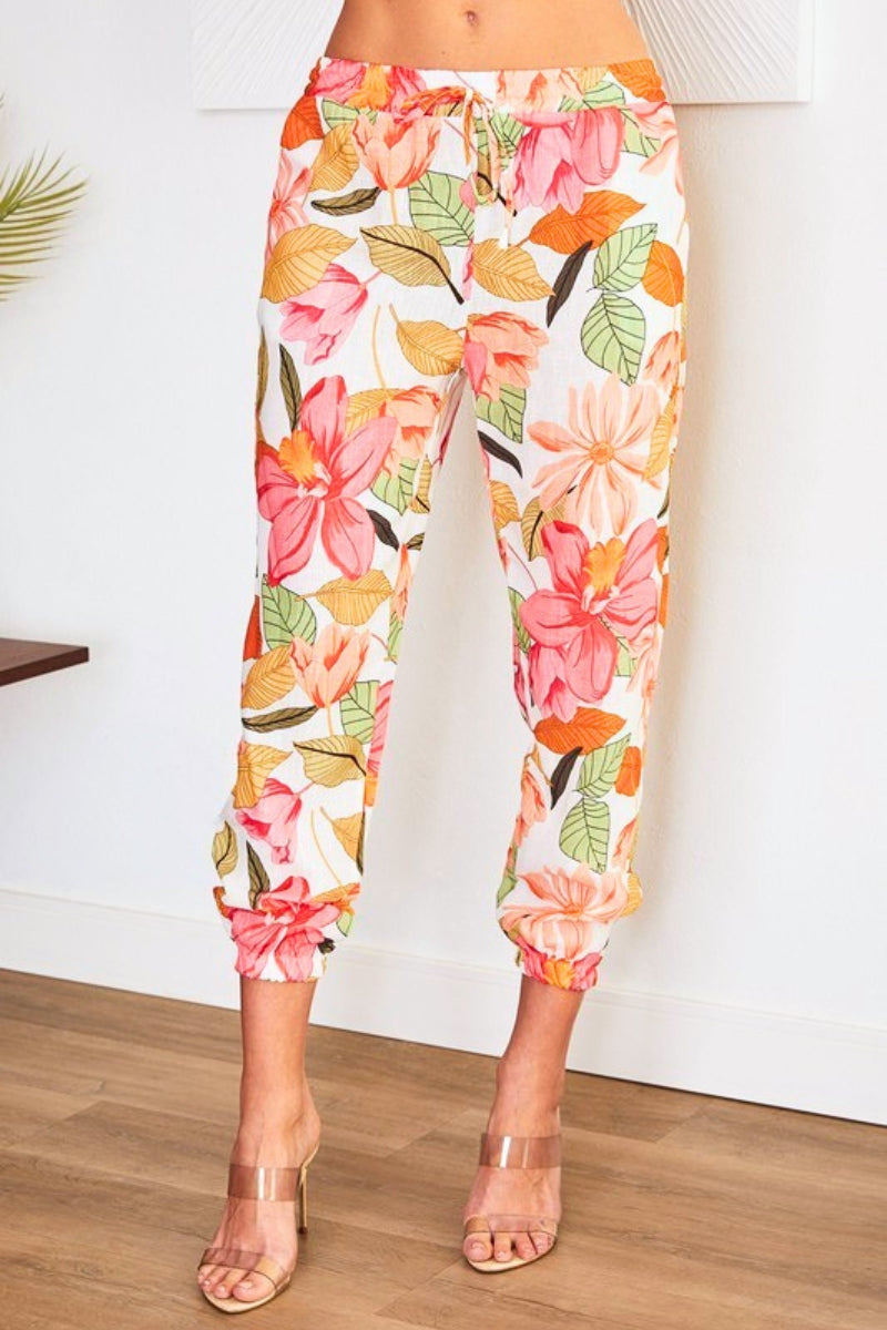 Colorful floral pants worn by a person on a wooden floor.
