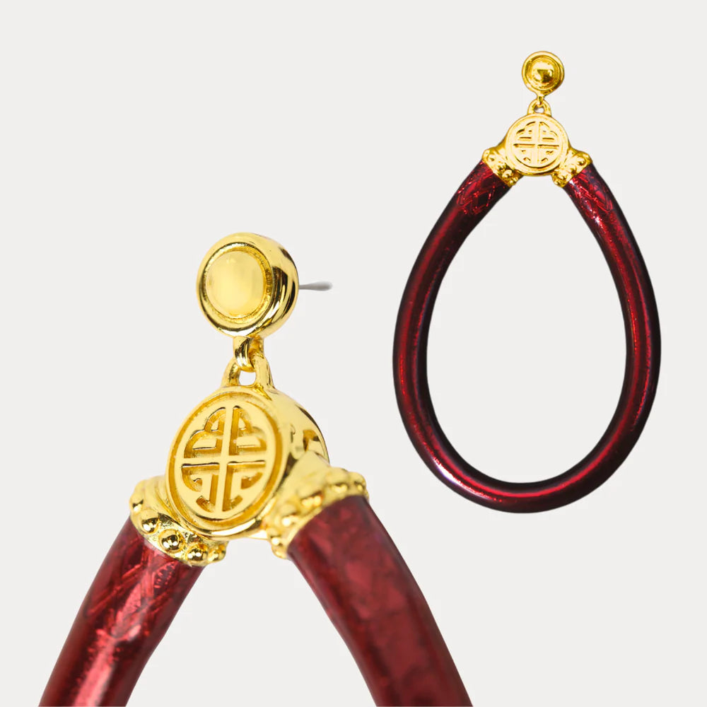 Gold and red earrings with intricate designs on a light gray background