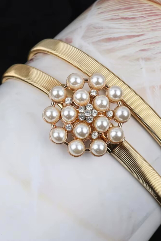 Gold belt with a central pearl design on a marble surface