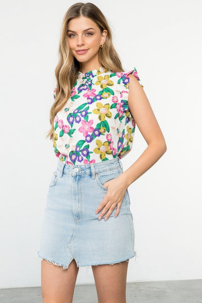 Woman wearing a colorful floral top and denim skirt on a white background