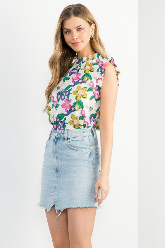 Woman wearing a colorful floral top and denim skirt on a white background