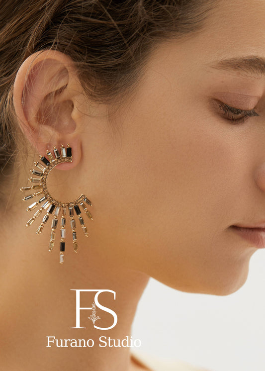 Close-up of a woman wearing a gold earring with 'Furano Studio' logo.