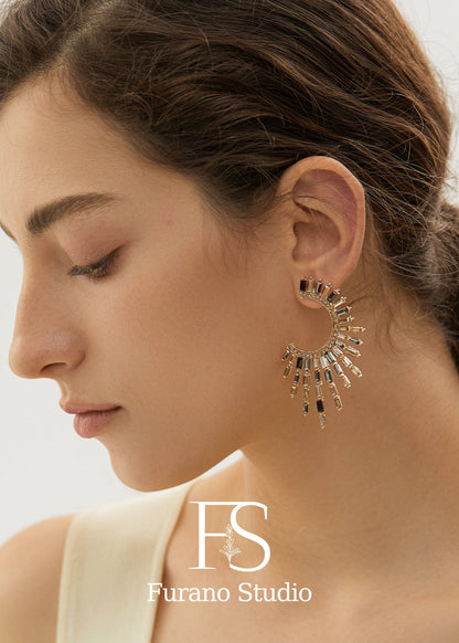 Close-up of a woman wearing a gold earring with 'Furano Studio' logo.