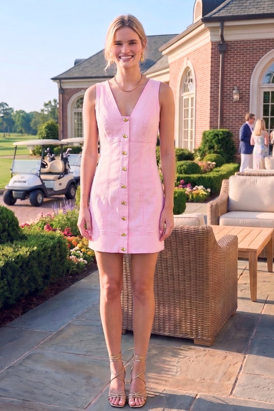 Woman in a pink dress standing outdoors near a building with a golf cart in the background.