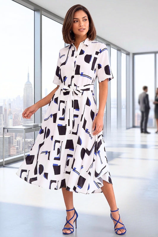 Woman wearing a patterned dress in an office setting with a cityscape view.