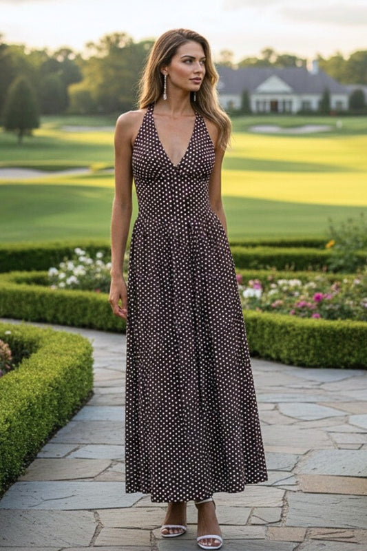 Woman in a black polka dot dress standing on a stone path with a golf course in the background