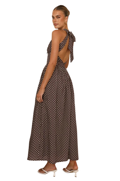 Woman wearing a polka dot dress with a cutout back on a white background