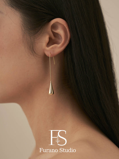 Gold earring worn by a person with Furano Studio logo