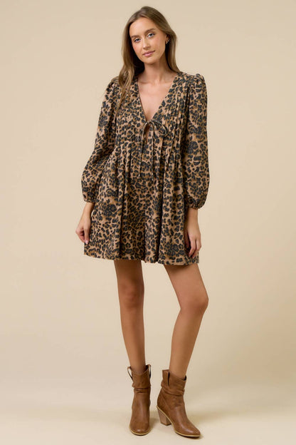 Woman wearing a leopard print romper with long sleeves on a beige background