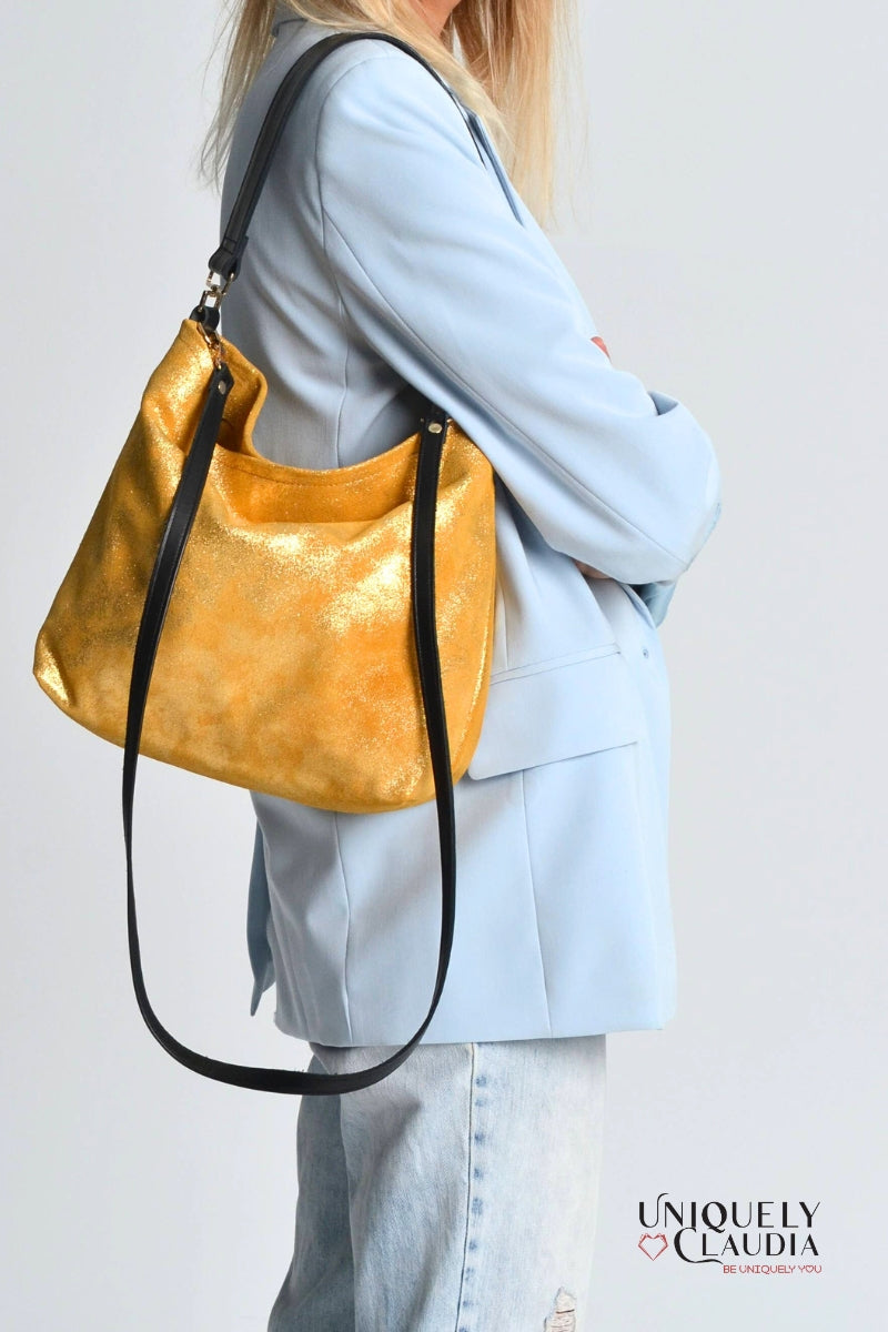Woman wearing a gold handbag with a plain background