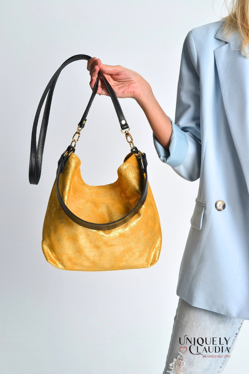 Woman holding a gold handbag with black straps 