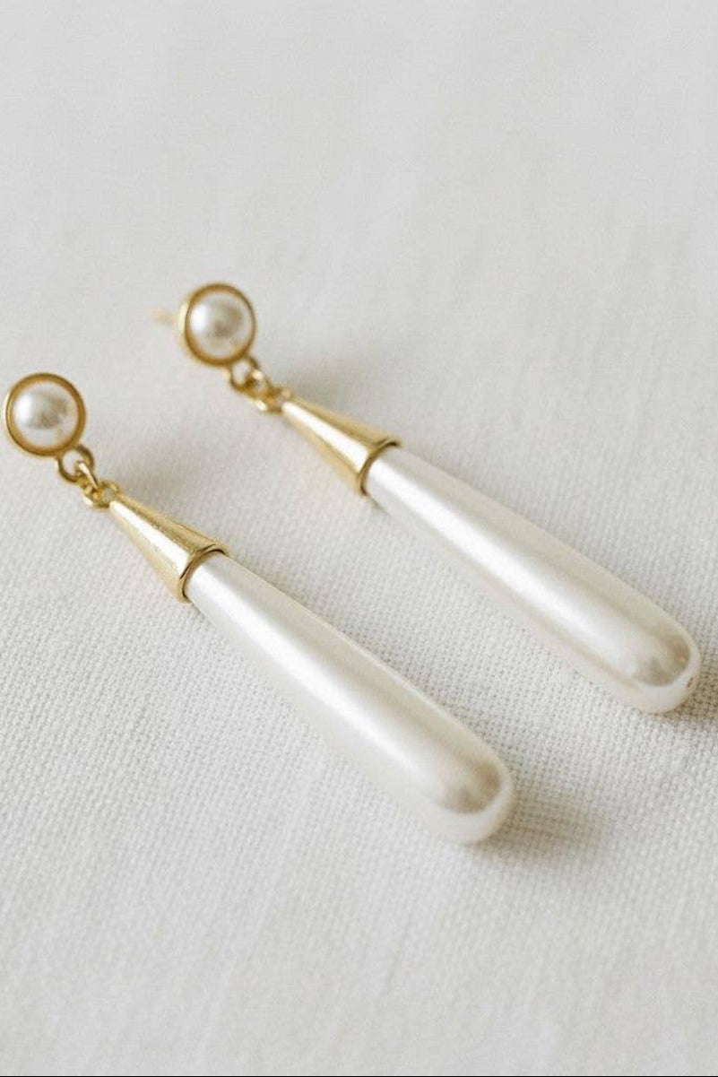 Pair of pearl earrings with gold accents on a light fabric background