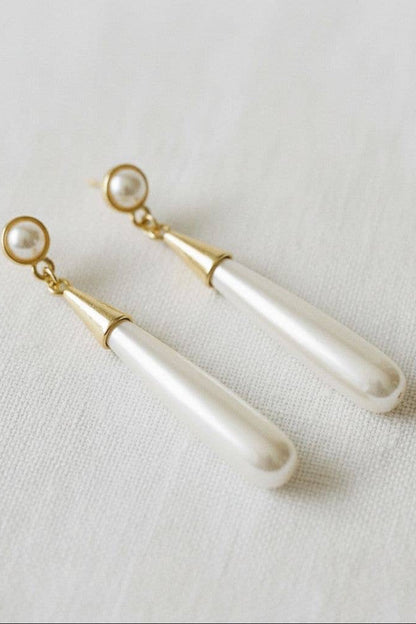 Pair of pearl earrings with gold accents on a light fabric background