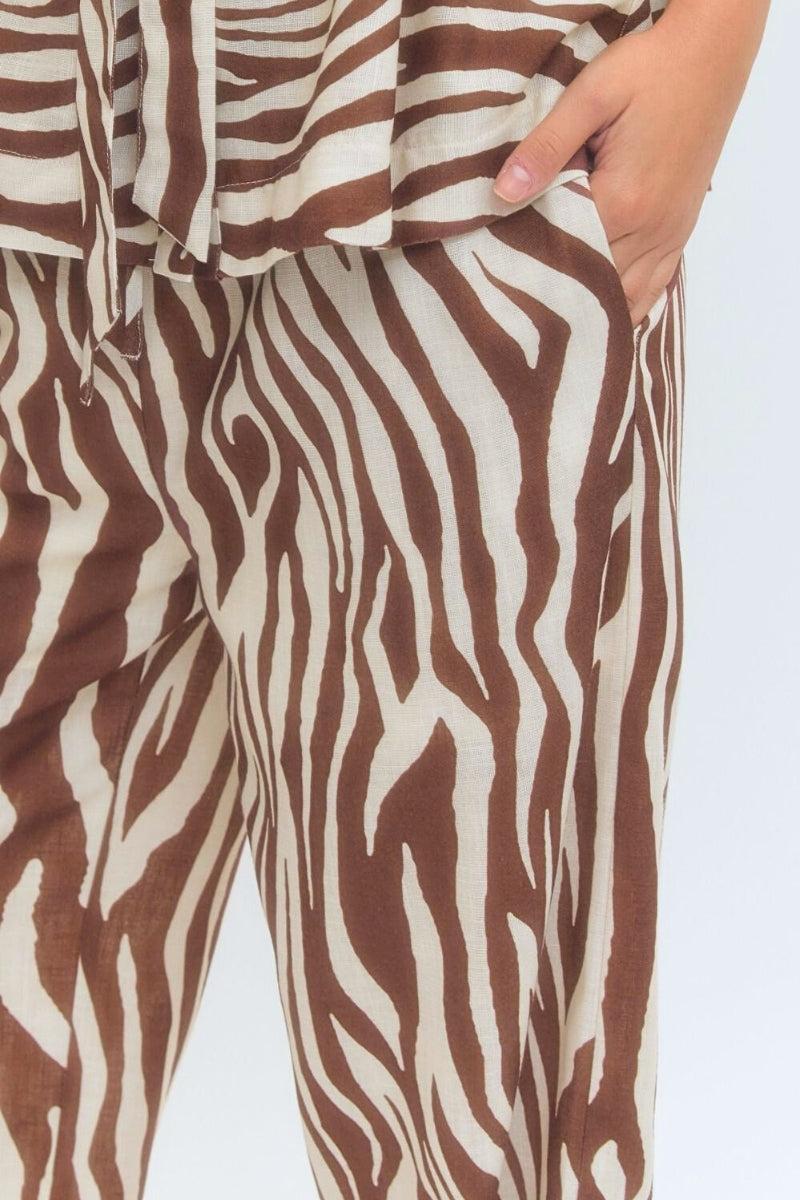 Brown and white zebra-striped pants with a person wearing them on a light gray background