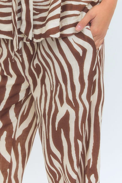 Brown and white zebra-striped pants with a person wearing them on a light gray background