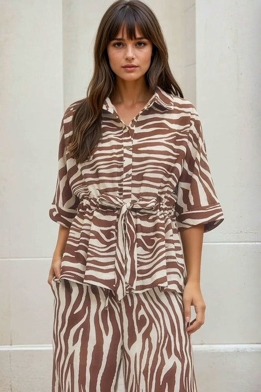 Woman wearing a brown and white patterned outfit against a neutral background
