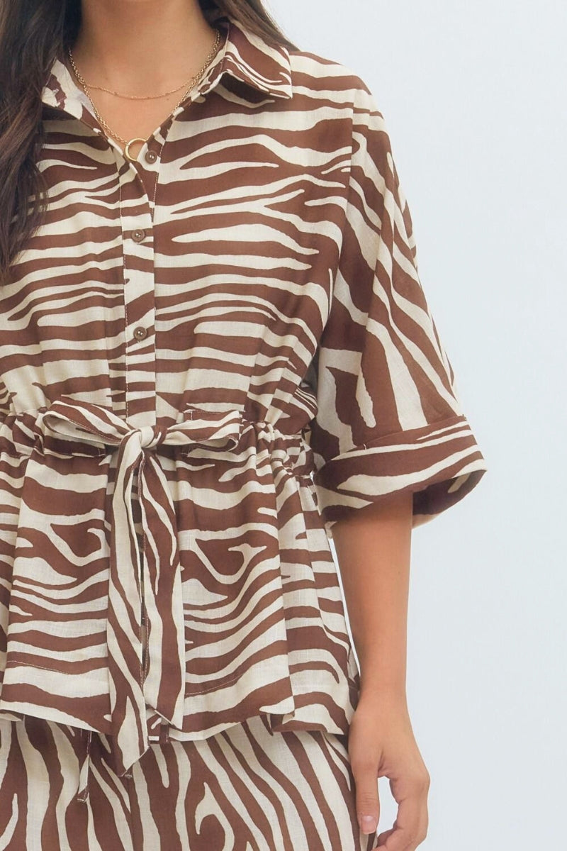Brown and white zebra patterned shirt worn by a person on a light gray background
