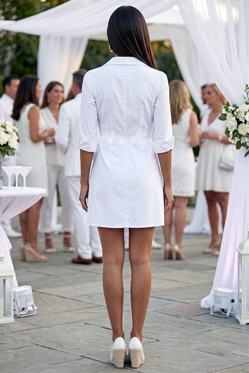 Woman in a white dress standing in front of a white canopy at an outdoor event.