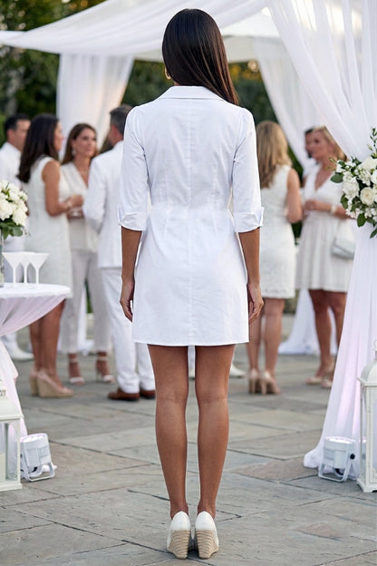 Woman in a white dress standing in front of a white canopy at an outdoor event.