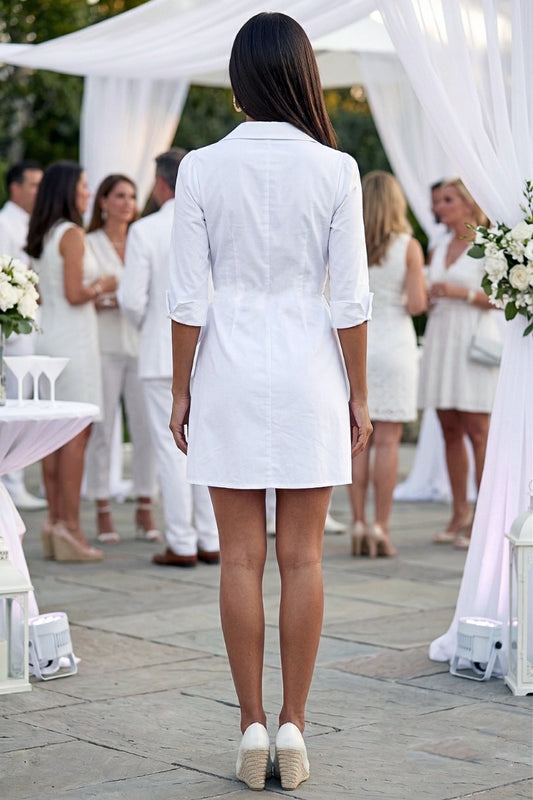 Woman in a white dress standing in front of a white canopy at an outdoor event.