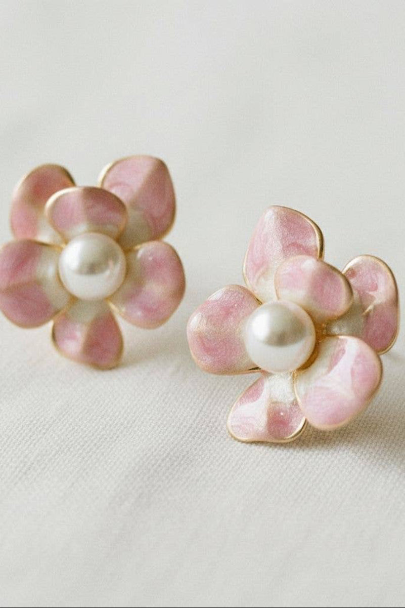 Pink flower-shaped earrings with pearl centers on a light background