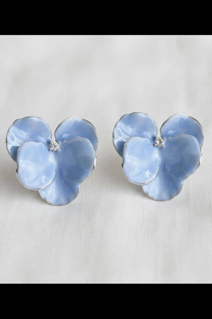 Pair of blue flower-shaped earrings on a light gray background