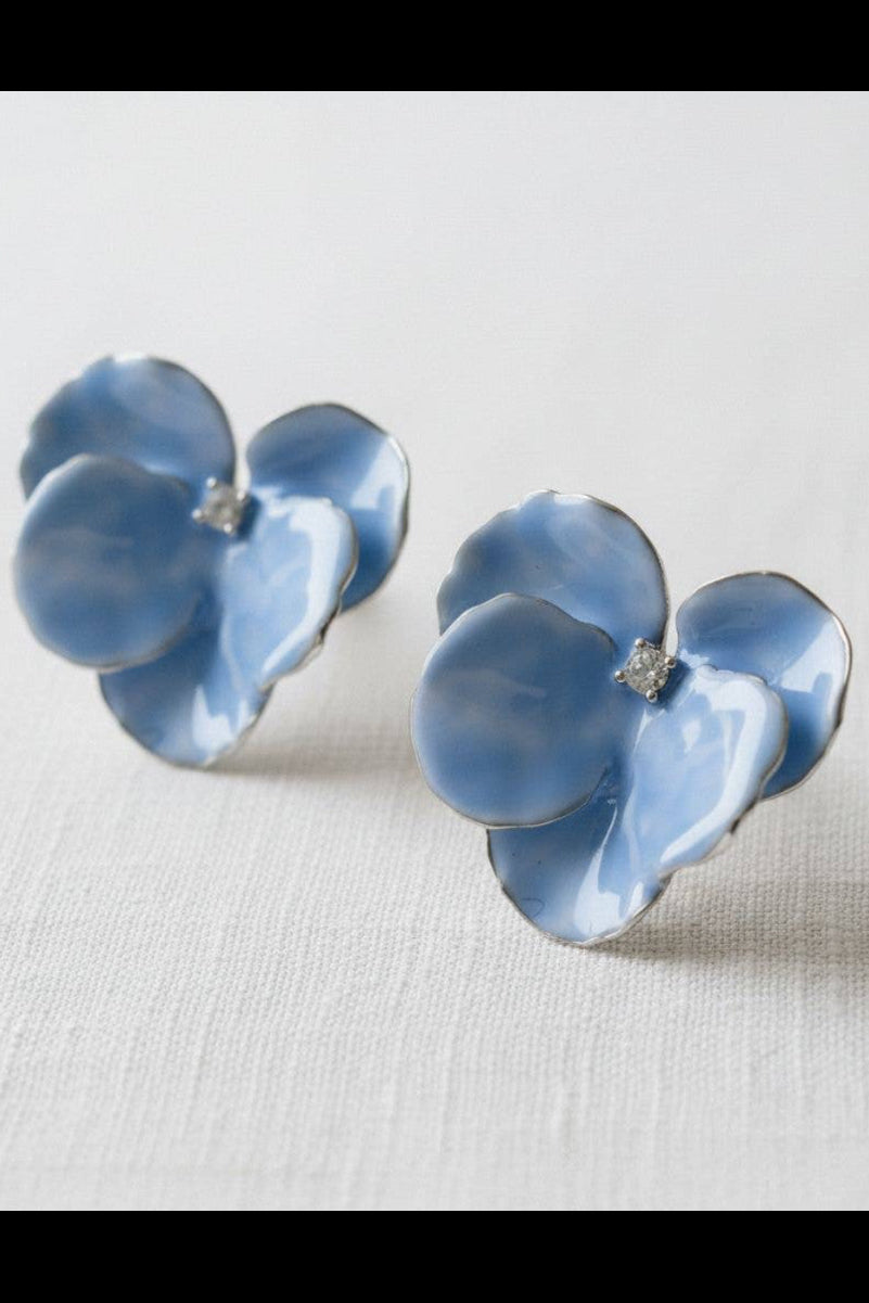 Pair of blue flower-shaped earrings on a light gray background