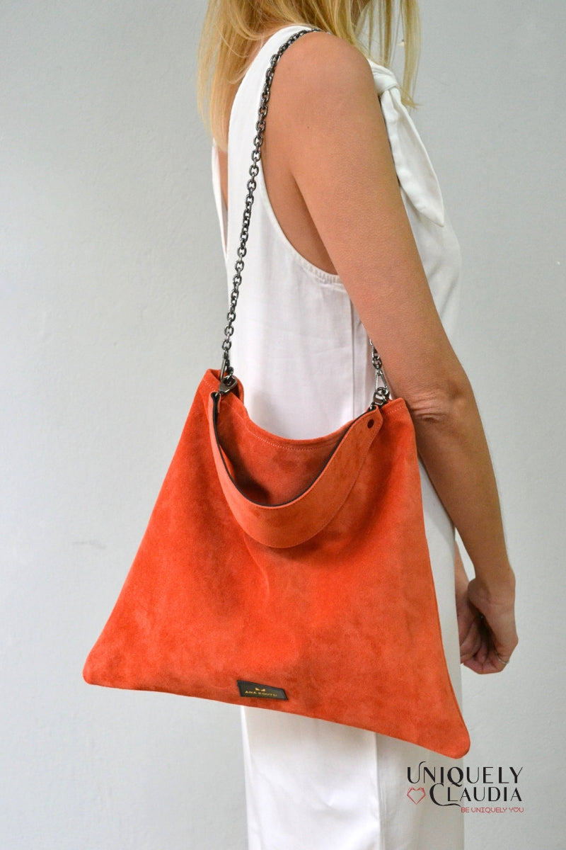 Orange handbag worn by a person on a plain background