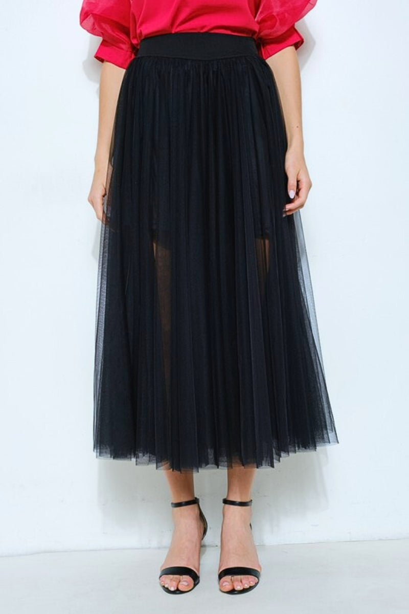 Person wearing a black tulle skirt with a red top on a white background