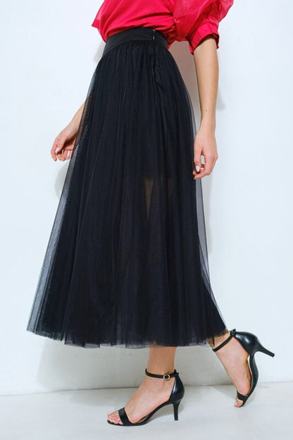 Person wearing a black tulle skirt and red top on a white background